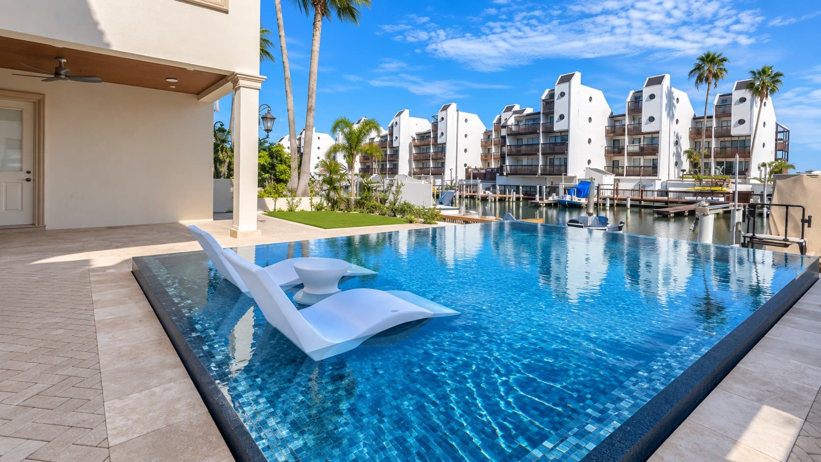 Glass-tile infinity pool with travertine deck built by Southern Gardens